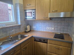 A kitchen with wooden cabinets, a stainless steel sink, a built-in microwave, a toaster, and a stove. - "Idyllic vacation apartment Seute Deern Kajüte - your perfect retreat on the (Juist)