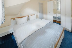 A bedroom with a bed, bedside tables, a wardrobe, and a mirror. - "Idyllic vacation apartment Seute Deern Kajüte - your perfect retreat on the (Juist)