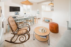 Ein stilvolles Wohnzimmer mit einem Schaukelstuhl, einem runden Couchtisch und einem Sofa.
