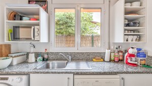 A kitchen with a built-in microwave, a sink, and a window with a view of a fence and trees. - Holiday Home 'Pineda 12' with Mountain View, Private Pool and Wi-Fi (Pals)