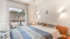 A bedroom with a bed, a nightstand, a chair, a table, and a view of the outside. - Holiday Home 'Pineda 12' with Mountain View, Private Pool and Wi-Fi (Pals)
