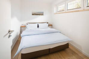 Ein Schlafzimmer mit einem Bett, Nachttischen, einem Fenster und einem Gemälde an der Wand.