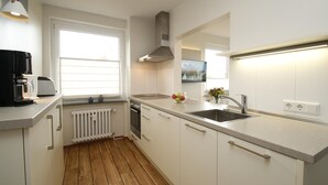 Eine moderne Küche mit weißen Schränken, einer Spüle aus Edelstahl und einem Fenster mit Jalousien.