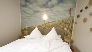 Ein Schlafzimmer mit einem Bett, Kissen, einem Nachttisch, einer Wanduhr und einer Wand mit runden Dekorationen.