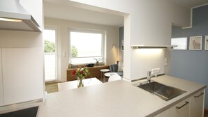 Eine moderne Küche mit einer großen Kochinsel, weißen Schränken und Blick zum Wohnbereich.