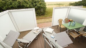 Eine Terrasse mit zwei Liegestühlen, einem Tisch mit Stühlen und Blick auf die Landschaft.