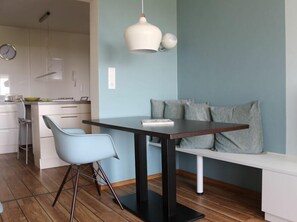 A modern dining area with a table, chairs, a bench, and a hanging light fixture. - "Relaxation and sea views: Your perfect vacation in Juist awaits you!" (Juist)