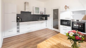 Een moderne keuken met witte kasten, een zwart aanrecht en een houten eettafel met een bloevas.