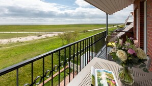 A balcony with a view of a green field and a cloudy sky. - Centrally located vacation apartment for 3 people (Juist)
