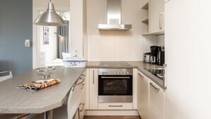 A compact kitchen with a built-in oven, a coffee maker, and a dining area with a bowl and magazine. - Centrally located vacation apartment for 3 people (Juist)
