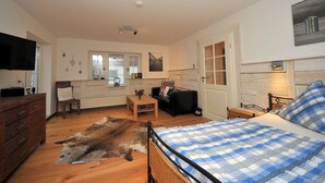 A room with a bed, a wooden dresser, a television, a desk, and a chair. - Cozy vacation apartment close to the beach (Juist)