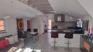 A modern kitchen with a central island, bar stools, and a dining area with a sofa and chairs. - Cozy vacation apartment close to the beach (Juist)