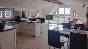 A modern kitchen with a dining area, large windows, and a staircase. - Cozy vacation apartment close to the beach (Juist)