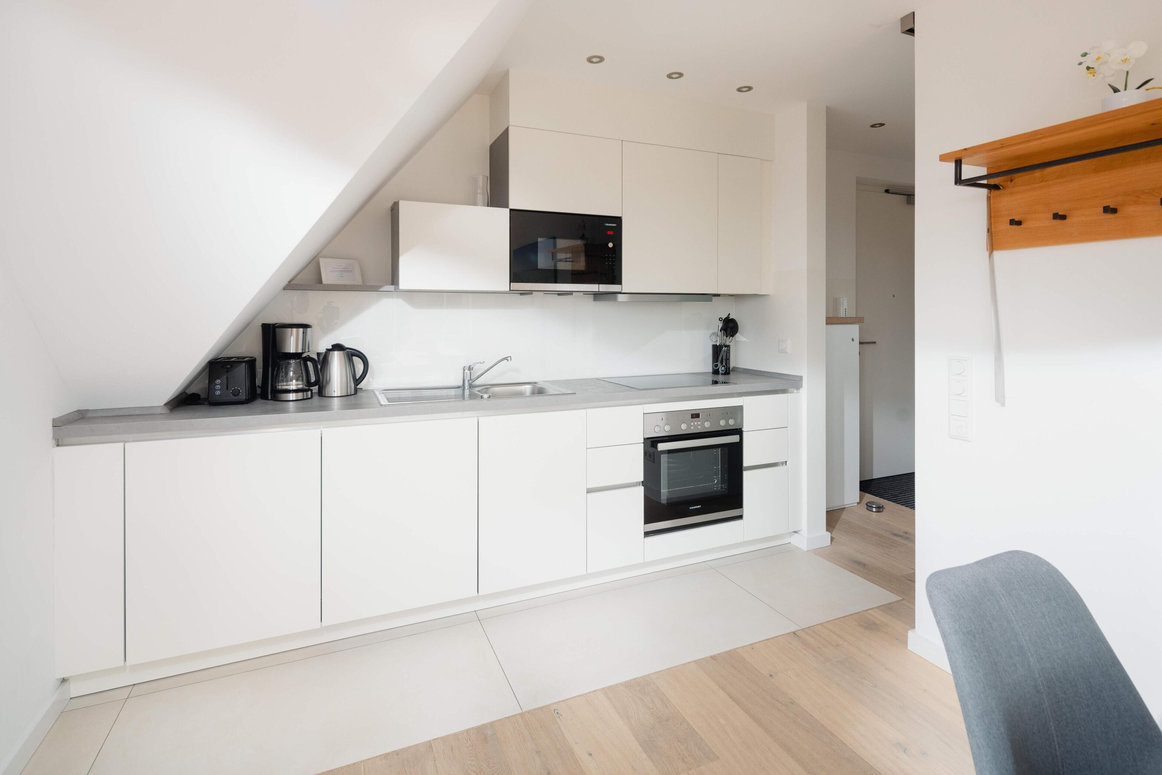 A modern kitchen with white cabinets, a built-in oven, a coffee maker, and a microwave.