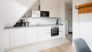 Una cocina moderna con armarios blancos, horno integrado, cafetera y microondas.