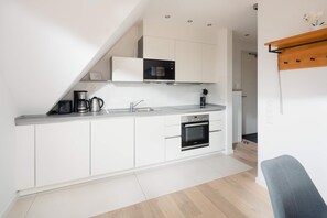 A modern kitchen with white cabinets, a built-in oven, a coffee maker, and a microwave. - Modern vacation apartment for 4 people, new building near the beach (Juist)