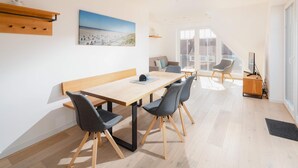 Un interior moderno con una mesa de madera, sillas, un sofá y un cuadro de un paisaje urbano.