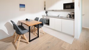 A compact kitchen with a dining table, chairs, and a microwave. - Modern vacation apartment for 2 persons, new building near the beach (Juist)