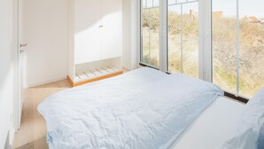 A bedroom with a large window, a wardrobe, and a bed. - Welcome to the "Strandmuschel" vacation apartment - Exclusive comfort on Juist (Juist)