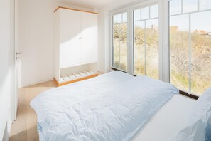 Ein Schlafzimmer mit großem Fenster, einem Kleiderschrank und einem Bett.