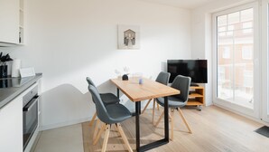 A modern kitchen with a dining table, chairs, and a TV. - Welcome to the "Strandmuschel" vacation apartment - Exclusive comfort on Juist (Juist)