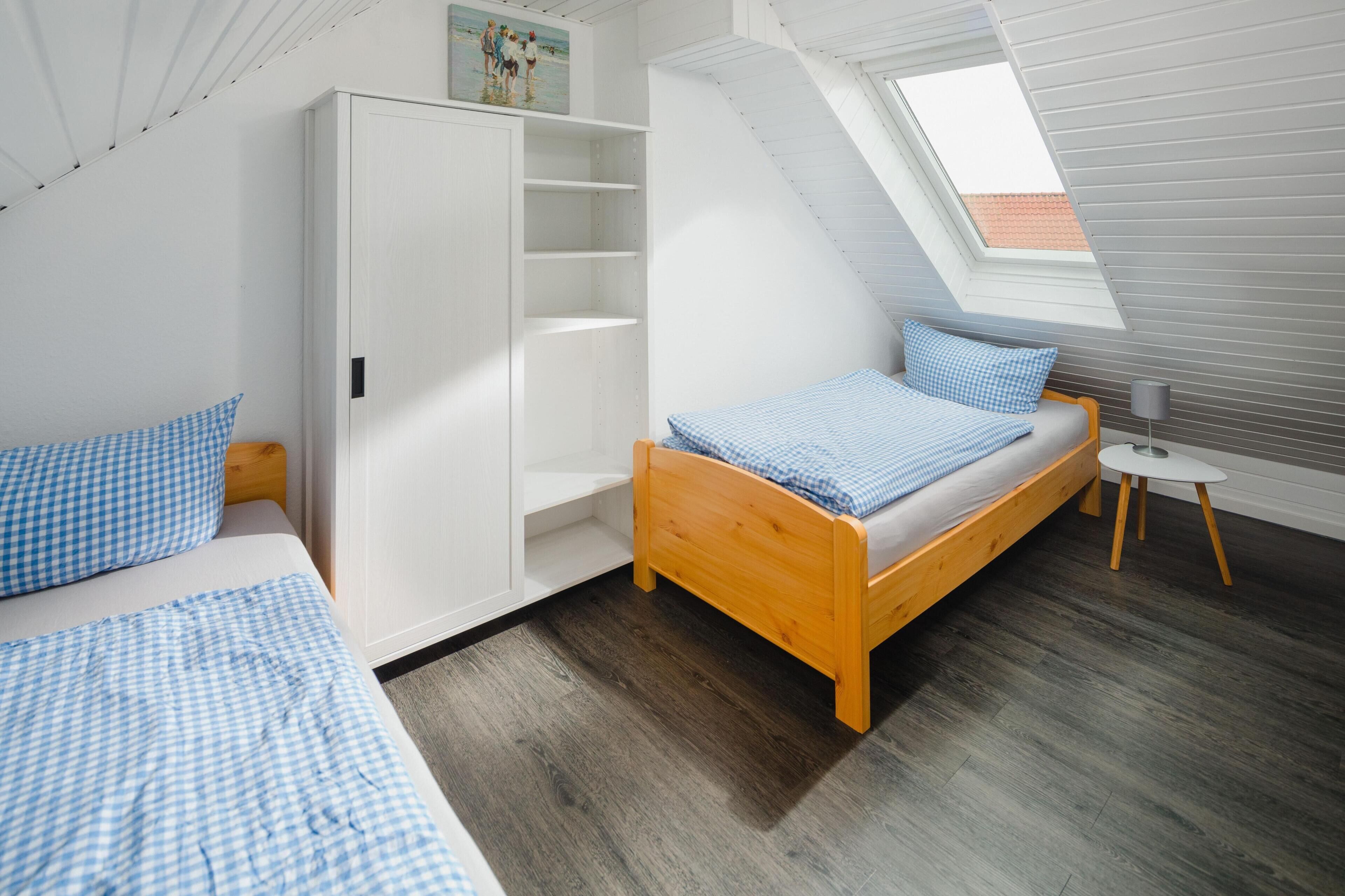 A bedroom with a sloped ceiling, a wooden bed, a wardrobe, and a skylight.
