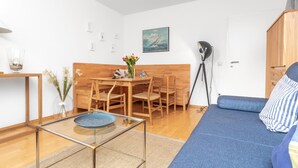 Uma sala de estar moderna com um sofá, uma mesa de centro de vidro, uma mesa de jantar com cadeiras e um banco de madeira.