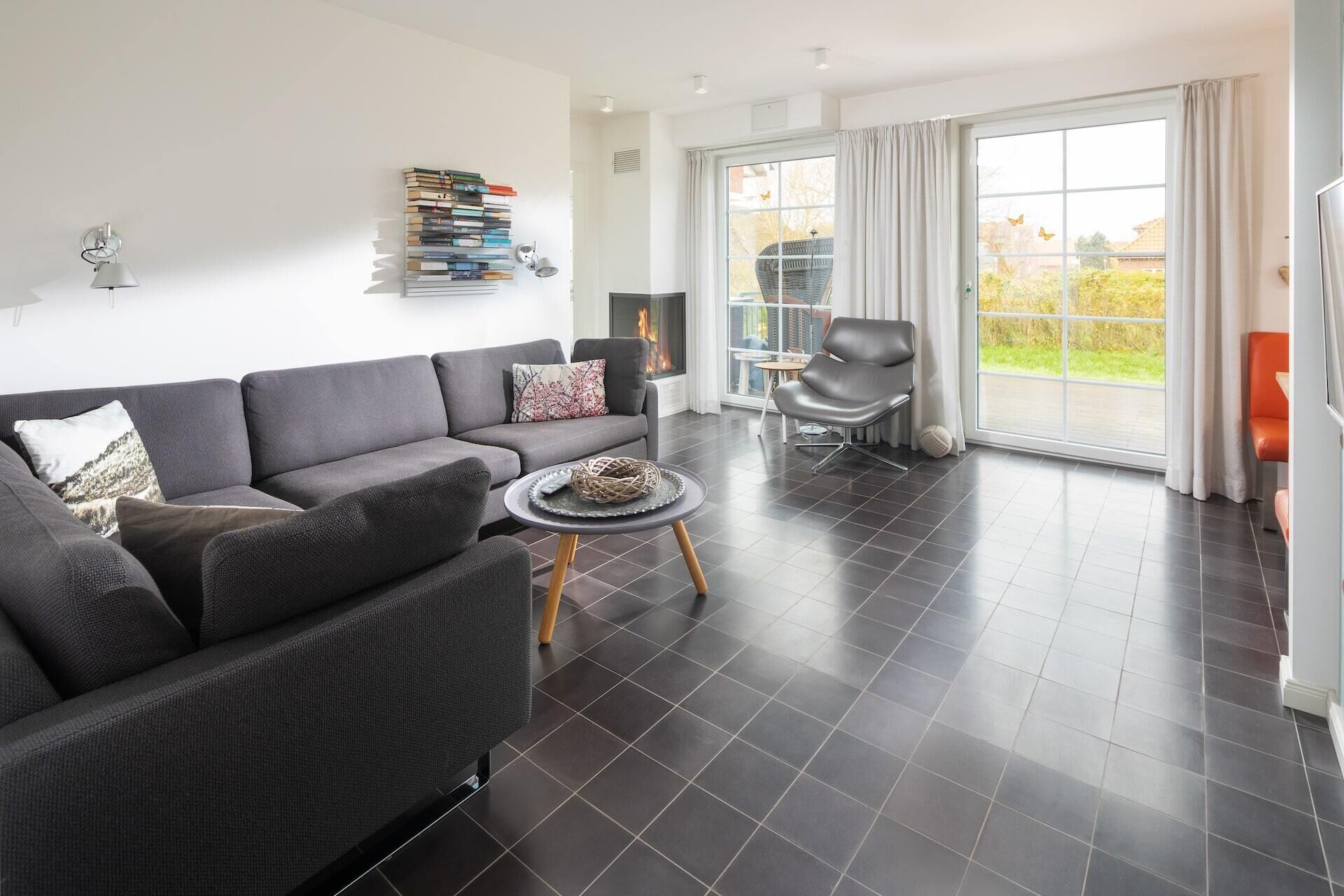 A modern living room with a grey sofa, a small round table, and a bookshelf.