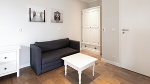 Une pièce avec un canapé gris, une table blanche et deux tableaux encadrés accrochés au mur.