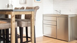 Une cuisine moderne avec une table à manger en bois, des appareils électroménagers en acier inoxydable et un dosseret de carrelage blanc.