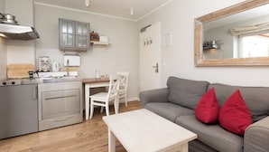 Ett kompakt bostadsutrymme med ett litet kök, en matplats och en sittgrupp med en soffa och ett soffbord.
