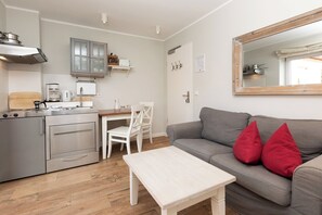 A compact living space with a kitchenette, a dining area, and a seating area with a sofa and a coffee table. - Apartment in a quiet location with balcony (Juist)
