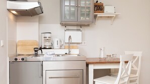 Ett kompakt kök med en inbyggd ugn, en kaffebryggare och ett handfat.
