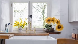Eine Küche mit Fenster, Spüle, Wasserhahn und einer Vase mit Sonnenblumen.