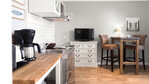 Una cocina con cafetera, televisor y comedor con sillas y mesa.