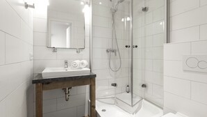 Un baño moderno con lavamanos, espejo, ducha e inodoro.