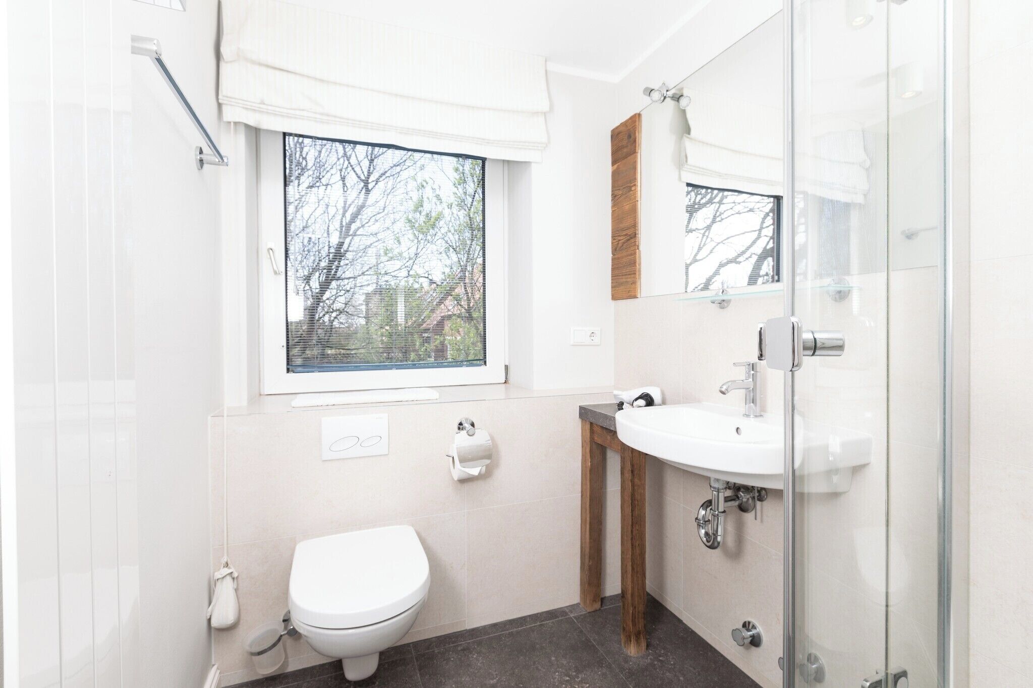 A modern bathroom with a toilet, sink, and window.