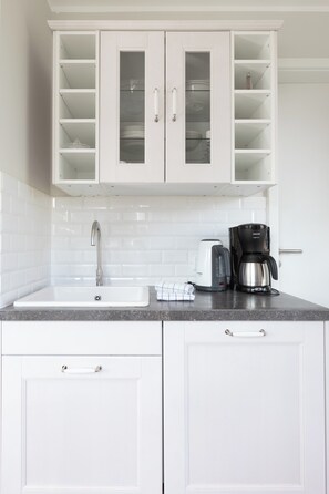 A kitchen with white cabinets, a sink, a coffee maker, and a kettle. - Apartment in a quiet location with balcony (Juist)