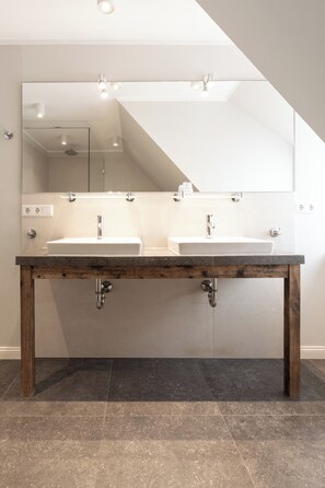 A bathroom with a double sink, wooden vanity, and a large mirror. - Apartment in a quiet location with balcony (Juist)