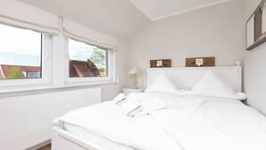 Ein Schlafzimmer mit einem Bett, zwei Nachttischen, einem Fenster und einer Heizung.