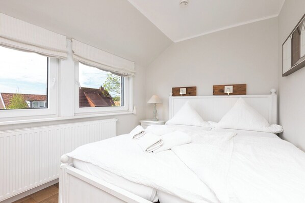 A bedroom with a bed, two bedside tables, a window, and a radiator. - Vacation apartment in a quiet location (Juist)