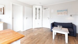 Ein Zimmer mit Holzboden, einem blauen Sofa, einem weißen Schrank und einem Holztisch.
