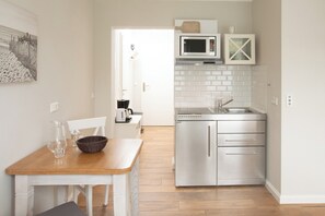 Eine moderne Küche mit weißen Schränken, einem Edelstahlkühlschrank, einer Mikrowelle und einem Spülbecken.