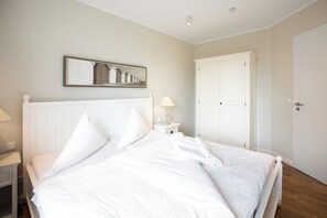 A bedroom with a bed, a nightstand, a lamp, a wardrobe, and a mirror on the wall. - Apartment in a quiet location with balcony (Juist)