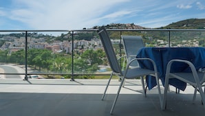 A balcony with a table and chairs, overlooking a hillside town. - Beach Apartment with Pool, Terrace & Parking (Velilla-Taramay)