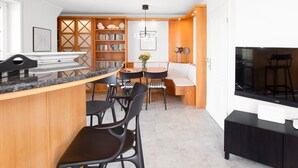 Uma cozinha moderna com área de refeições, armários de madeira e televisão de tela plana.