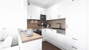 A modern kitchen with white cabinetry, a wooden countertop, a built-in oven, a coffee machine, and a dishwasher. - "Fantastic vacation apartment with sea view and exclusive furnishings on Juist!" (Juist)