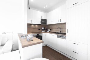 A modern kitchen with white cabinetry, a wooden countertop, a built-in oven, a coffee machine, and a dishwasher. - "Fantastic vacation apartment with sea view and exclusive furnishings on Juist!" (Juist)