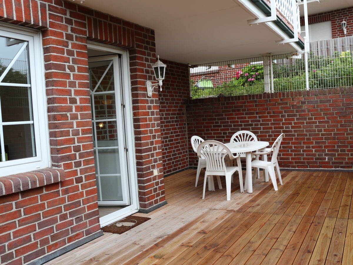 Un patio con tavolo e sedie, un muro in mattoni e una porta.
