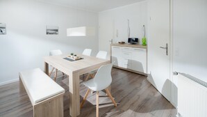 Uma cozinha moderna com armários brancos, bancada de madeira e micro-ondas.